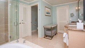 Un bany amb plat de dutxa de vidre, banyera, un lavabo amb rentapèns i un vàter.