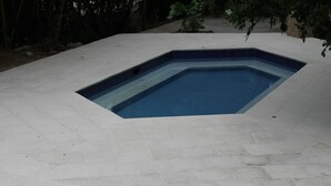 En pool med en geometrisk design, omgiven av en terrass med kakelplattor.