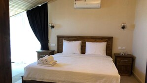 A neatly made bed with white linens, a wooden headboard, and a wall-mounted air conditioner. - Nehir Suit Hotel (Ortaca)