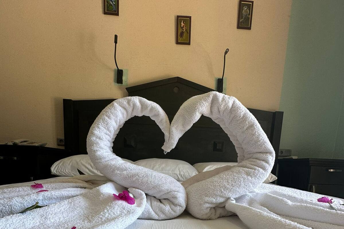 Ein Hotelzimmer mit einem Bett, dekoriert mit einer herzförmigen Handtuchanordnung.