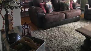 A living room with a brown leather sofa, a wooden coffee table, and a rug. There is a dining table with chairs in the background. - OUR HOME ...AWAY FROM HOME (Laurel Springs)