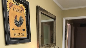 A hallway with a framed sign reading "Farm House," a rustic mirror, a wooden console table with various items, and a trash can labeled "POST." - OUR HOME ...AWAY FROM HOME (Laurel Springs)