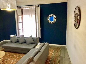 A living room with a grey sofa, a patterned rug, and a decorative wall piece. - Terrazas al Pilar, apartment with views for 8 people (Zaragoza)