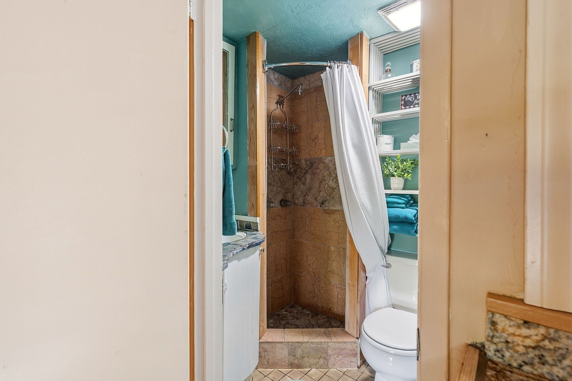 Ein schmales Badezimmer mit Dusche, Toilette und Ablage für Toilettenartikel.