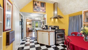 A kitchen with a checkered floor, a stove, an oven, and a dining table with a red tablecloth. - Night Owl - Murphys Vacation Rentals (Murphys)