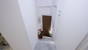 A narrow staircase with white walls and a marble floor leading to a door. - Alfieri rooms - flat Conchiglia (Atrani)