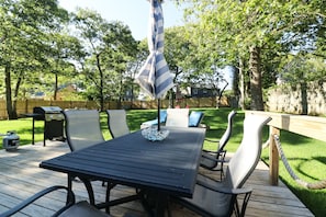 Relax on the patio surrounded by lush greenery and enjoy meals under the shade of a striped umbrella.