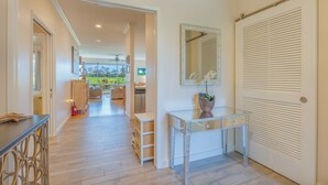 A hallway with a view of a garden, a dining area, and a kitchen. - Relaxing Princeville Retreat • Golf Course + Sunset Views • A/C & Pool (Princeville)