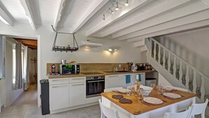 Uma cozinha moderna com armários brancos, uma mesa de jantar de madeira e uma escada.