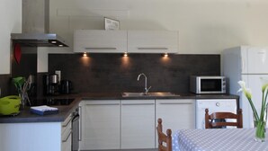 Eine kleine Küche mit weißen Schränken, einer Mikrowelle, einem Spülbecken und einem kleinen Kühlschrank.