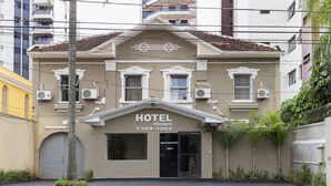 Un hotel con fachada color beige, techo de tejas y varios equipos de aire acondicionado.