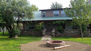 A two-story house with a stone wall and a fire pit in the front yard. - Family-Friendly 4BR Ranch Home Near Sedona w/ Porch, Fire Pit & Private Spa (Cottonwood)