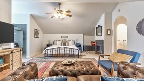 A bedroom with a bed, a television, a ceiling fan, a fireplace, and a large mirror. - Family-Friendly 4BR Ranch Home Near Sedona w/ Porch, Fire Pit & Private Spa (Cottonwood)