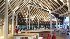 Een modern restaurant met een hoge plafond en houten balken, met een centraal bar gedeelte met krukken en een toonbank.