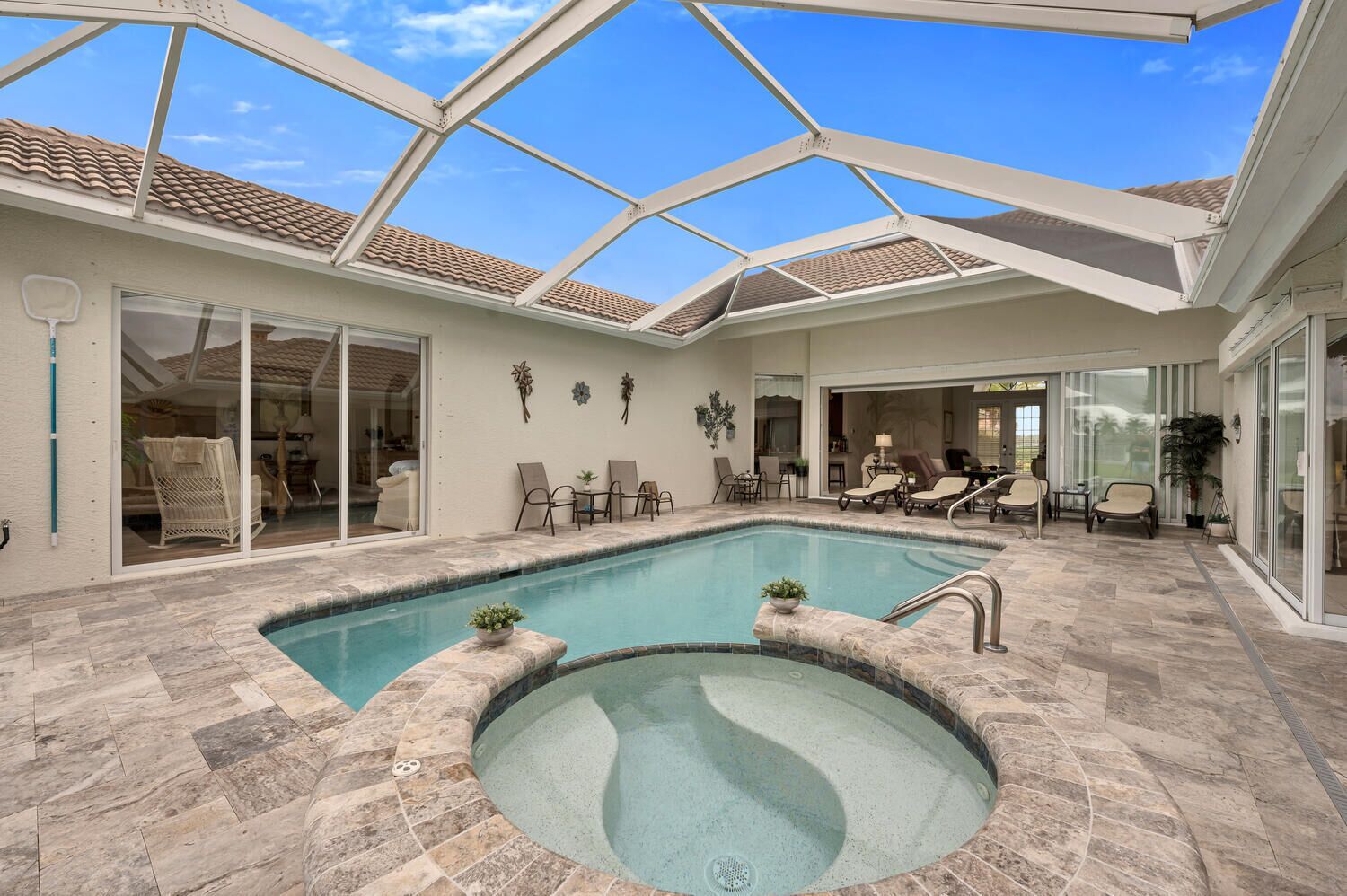 Un espace piscine comprenant un jacuzzi, des chaises longues et un patio couvert.