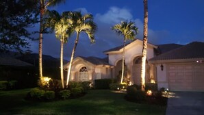 Una casa residencial con entrada de vehículos, palmeras y garaje.