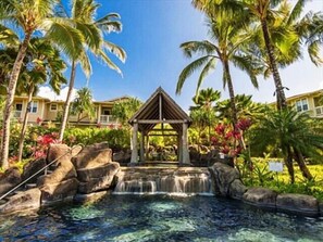 Un resort con piscina cristallina, una piccola cascata e palme.