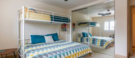 A bedroom with bunk beds, a ceiling fan, a mirror, and a small table.