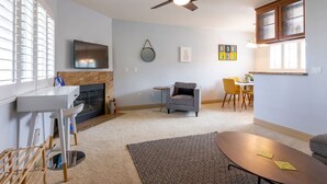 Una sala de estar moderna con chimenea, ventilador de techo, televisor y comedor.