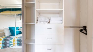 Una habitación de hotel moderna con un vestidor que contiene toallas dobladas con esmero y un perchero.