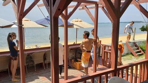 A wooden deck with outdoor seating and umbrellas overlooking a beach. - Beach Plus (Onna)
