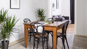 A dining area with a wooden table and chairs, potted plants, and a hanging light fixture. - Live Life Ermou (Athens)