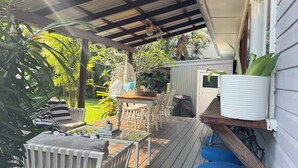 A covered outdoor patio with a wooden table and chairs, surrounded by lush greenery. - The Miami Beach vacation home (Miami)