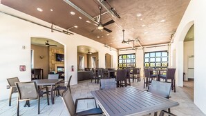 Un vaste espace de restauration intérieur, doté de nombreuses tables et chaises, d’un ventilateur de plafond et de grandes fenêtres laissant entrer la lumière naturelle.