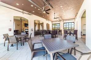 Enjoy meals in a spacious dining area with multiple tables and chairs, illuminated by recessed lighting and ceiling fans.