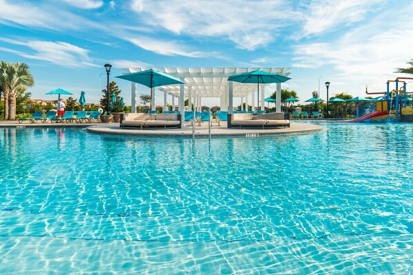 Relax by the serene pool surrounded by palm trees and lush vegetation.