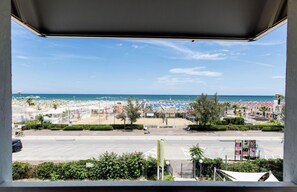 Vista de la playa desde un espacio cubierto con sombrillas y sillas.