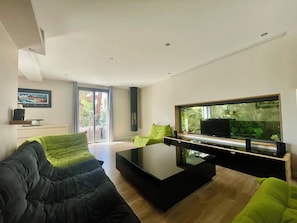A modern living room with a large flat-screen TV, a black coffee table, and a green sofa.