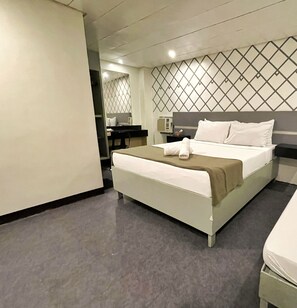 A hotel room with a bed, a desk, and a mirror.