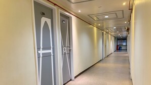 A long, narrow hallway with doors on one side and a trash bin on the other. - ACME Inn Subic (Olongapo)