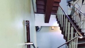 A staircase with a handrail and a black mat at the bottom. - ACME Inn Subic (Olongapo)