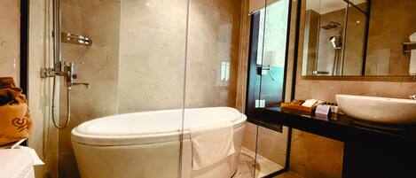 A modern bathroom with a large bathtub, a glass-enclosed shower, and a vanity with a sink.