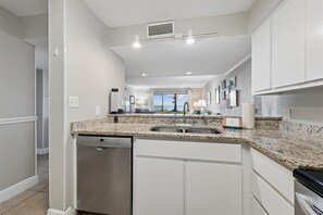 A modern kitchen with granite countertops, stainless steel appliances, and a view to the outside.
