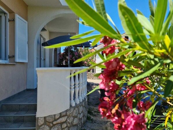 A building with a stone wall, a white balcony with balusters, and a clear blue sky.