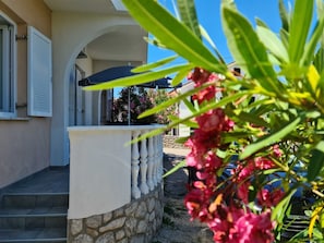 A building with a stone wall, a white balcony with balusters, and a clear blue sky.