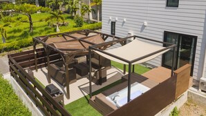A rooftop deck with a hot tub, wooden furniture, and a view of a landscaped garden. - Villa Garden Onna (Onna)