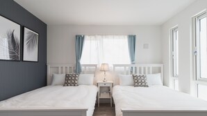 A hotel room with two single beds, a nightstand with a lamp, and a window with curtains. - Villa Garden Onna (Onna)
