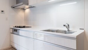 A modern kitchen with white cabinetry, a stainless steel sink, and a built-in range hood. - Villa Garden Onna (Onna)