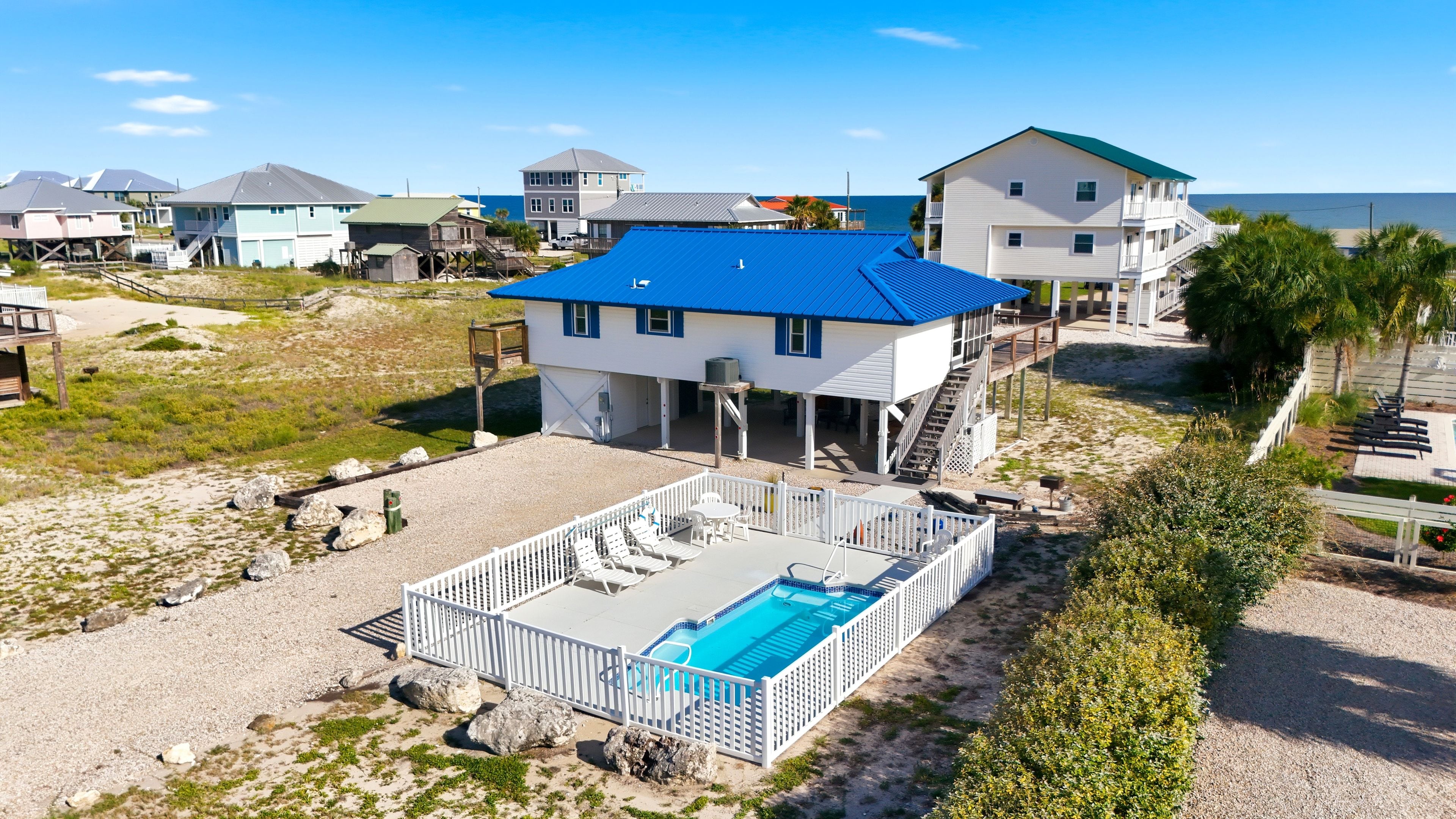 A beachfront property with a swimming pool, multiple buildings, and a clear view of the ocean.