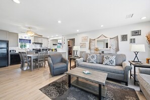 Un salon moderne comprenant un canapé, des fauteuils, une table basse et un coin repas avec des chaises et une table.
