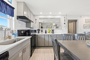 A modern kitchen with stainless steel appliances, a dining area with a table and chairs, and a view of the outside.