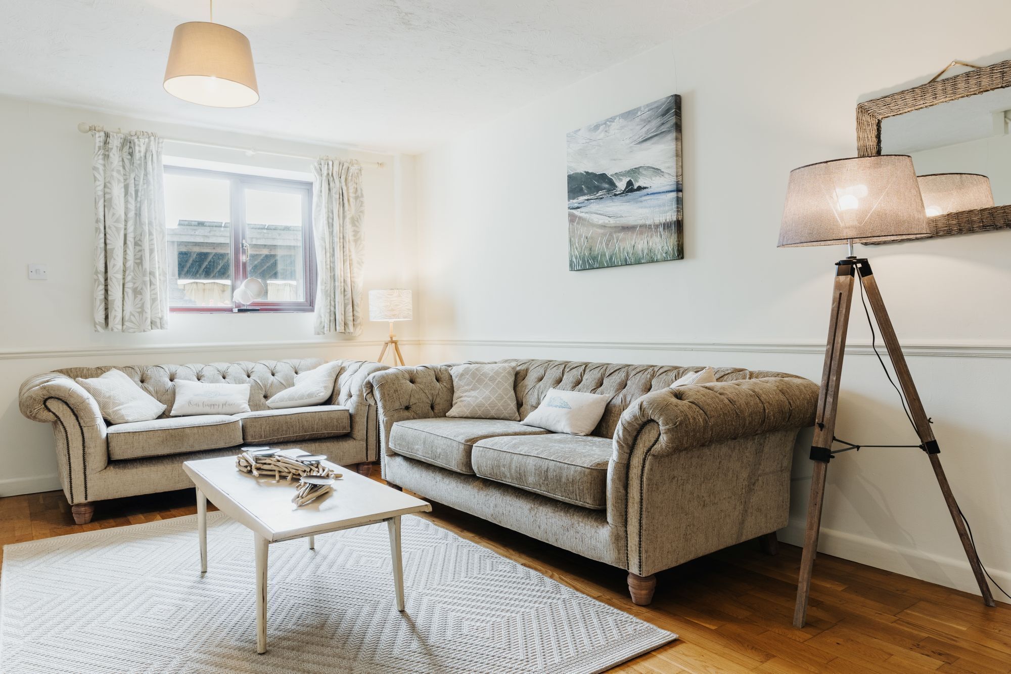 A living room with a sofa set, a coffee table, a floor lamp, and a painting on the wall.