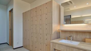 A modern bathroom with wooden lockers, a sink, and a mirror.