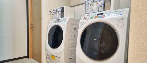 A laundry room with two front-loading washing machines and a control panel above them.