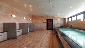 A modern indoor swimming pool area with a wooden floor, stone walls, and a glass barrier. - CABIN & HOTEL ReTIME - Hostel (Naha)