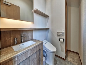 Un baño moderno con tocador de madera, un lavabo, un inodoro y un dispensador de toallas.